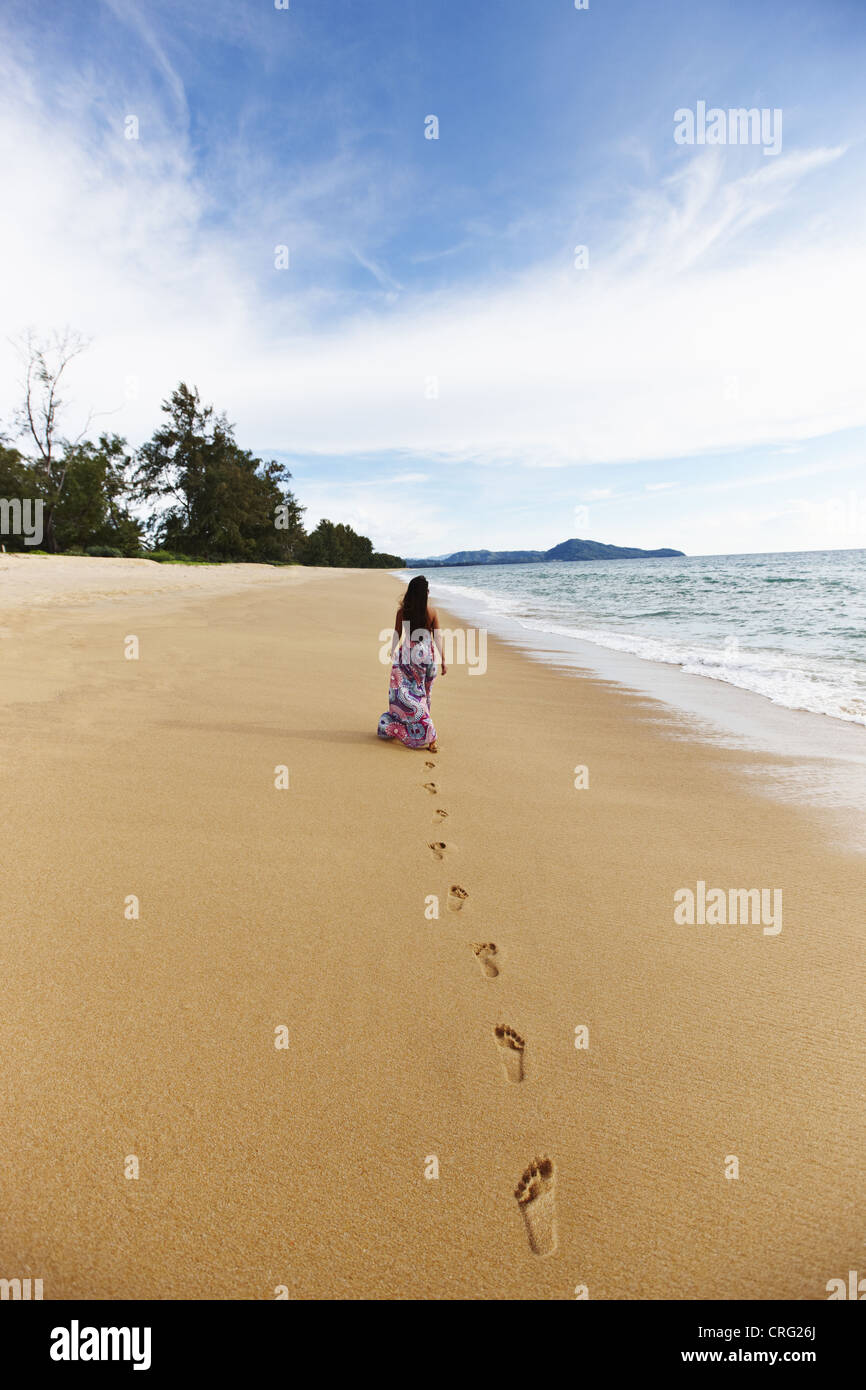 Woman making footprints on sandy beach Banque D'Images