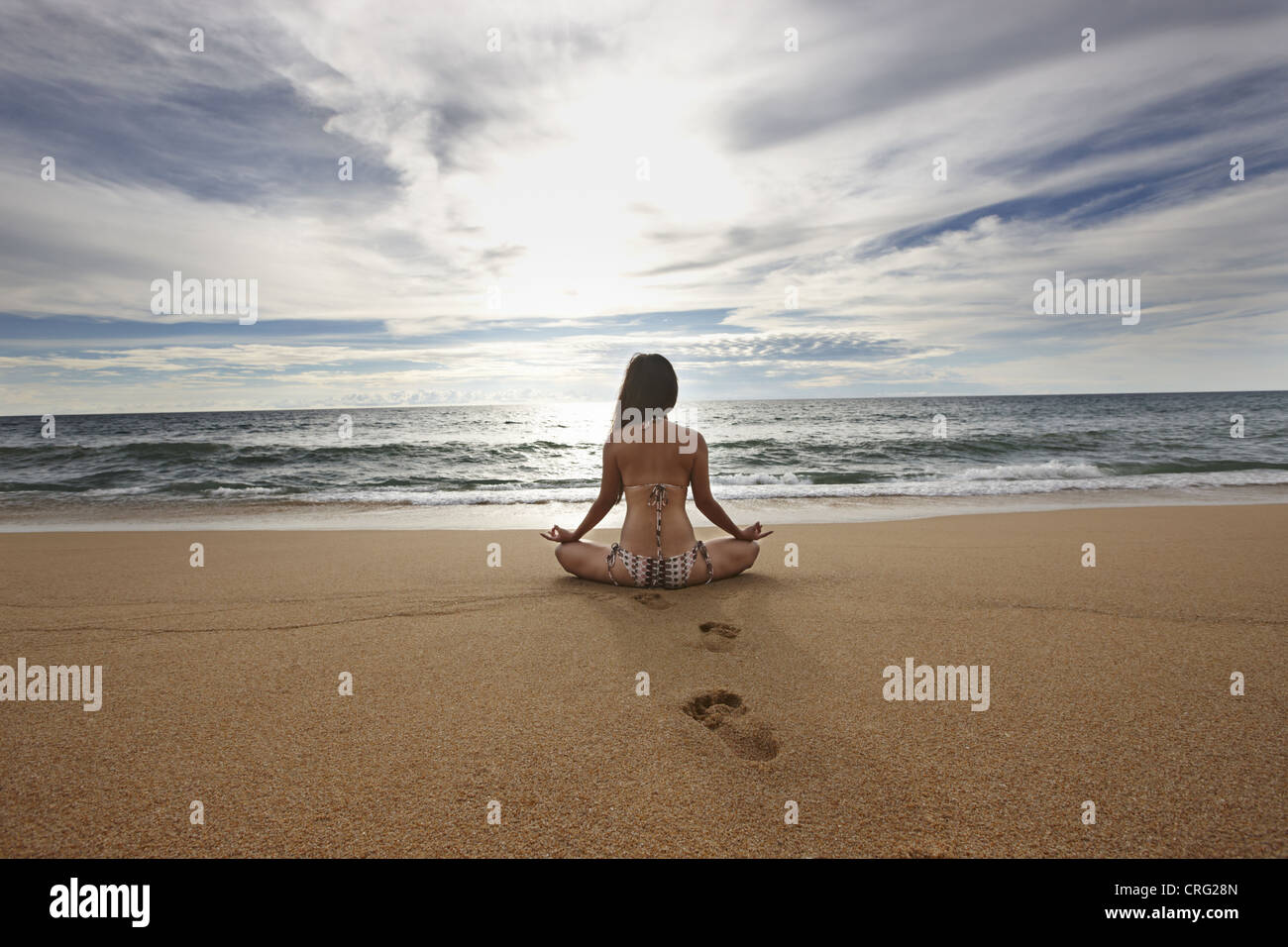 Woman meditating on sandy beach Banque D'Images