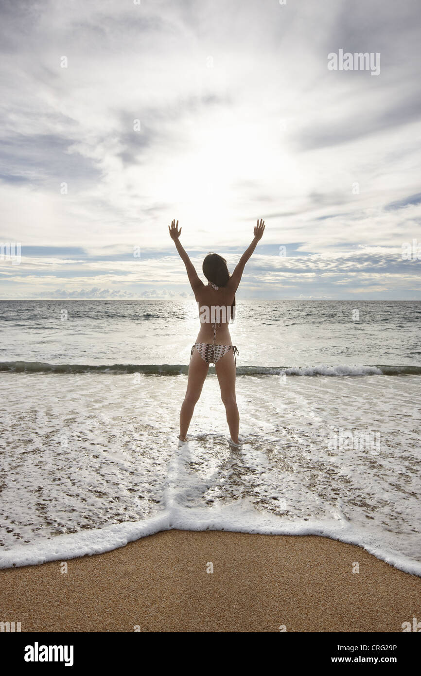 Femme debout en surf on beach Banque D'Images