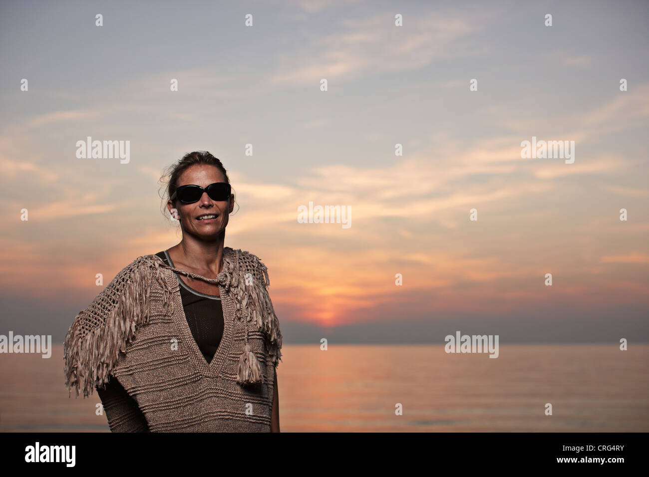 Woman standing on beach at sunset Banque D'Images