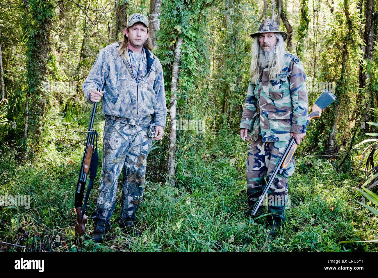 Un portrait de deux hommes aux cheveux longs portant des fusils de  camouflage et la tenue dans l'épaisse forêt Photo Stock - Alamy