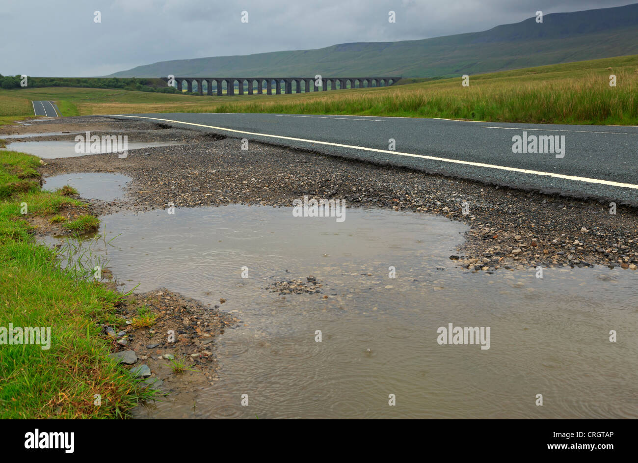 Un jour de pluie dans le Nord du Yorkshire. Les flaques d'eau à côté de la B6255 et d'un viaduc Ribblehead vu de Misty. Banque D'Images
