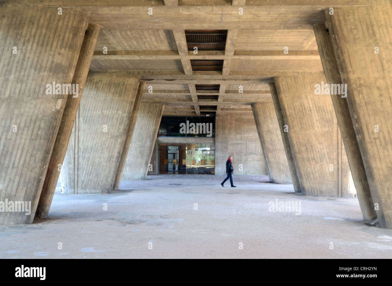 L'homme passe devant l'entrée et les colonnes en béton ou Pilotis of L'unité de logement Cité Radieuse ou unité d'habitation par le Corbusier Marseille France Banque D'Images