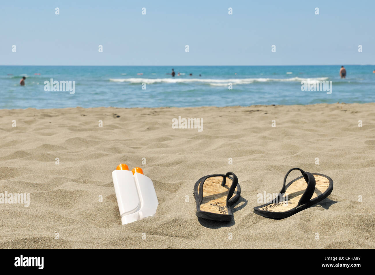 Les chaussons et la crème solaire sur la plage stock photo Banque D'Images