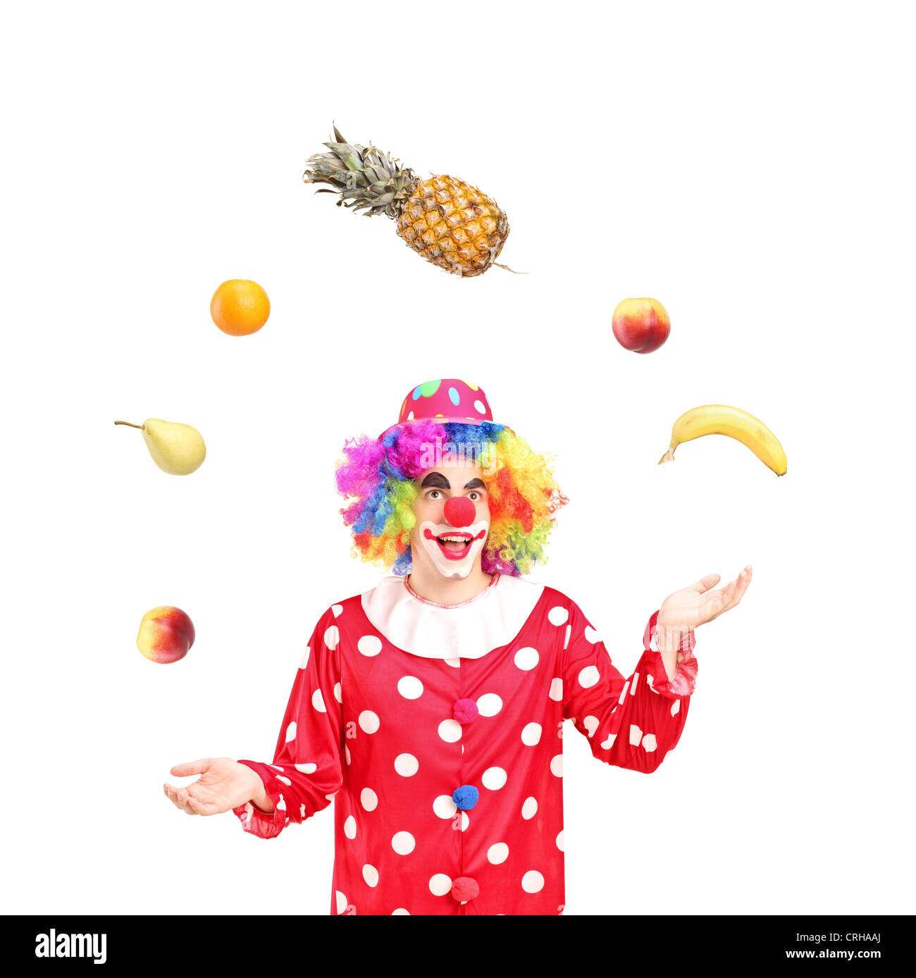 A smiling clown jonglant avec fruits isolés contre fond blanc Banque D'Images