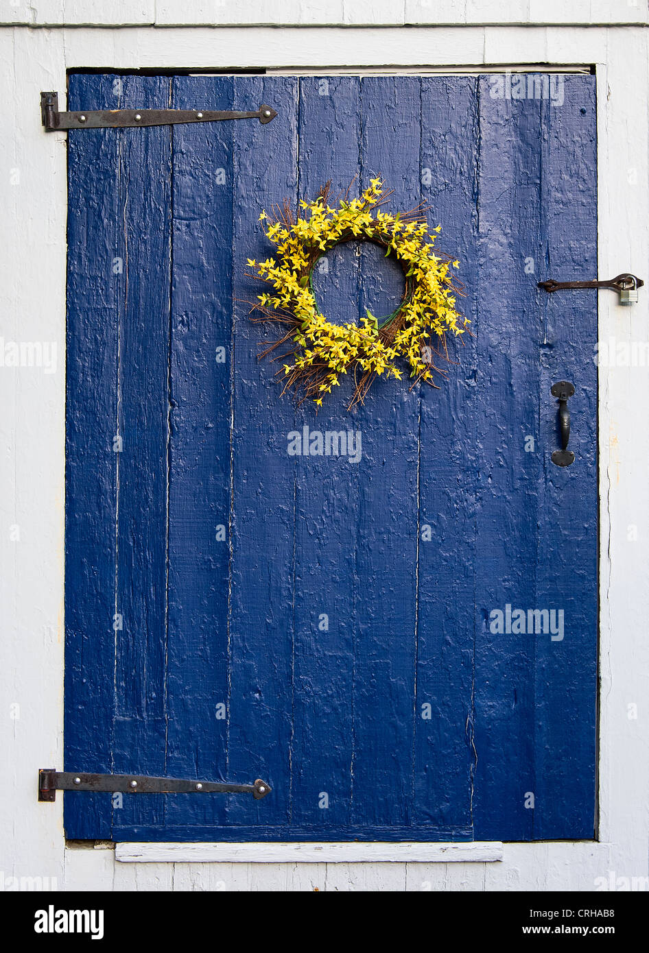 Couronne de fleurs simples bleu rustique sur porte. Banque D'Images