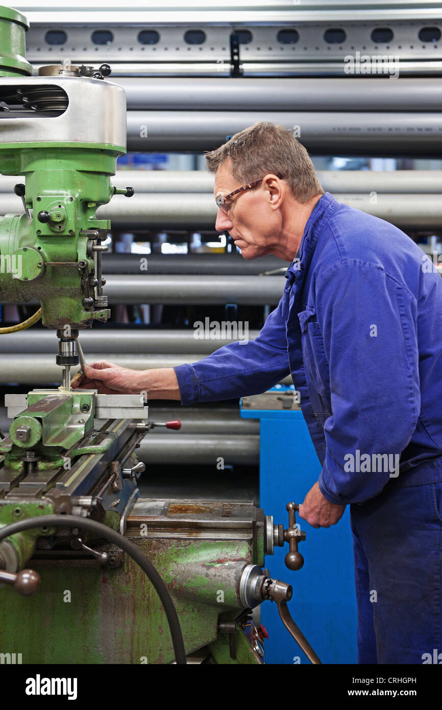 Homme d'âge moyen derrière une machine industrielle dans un atelier de mécanique Banque D'Images