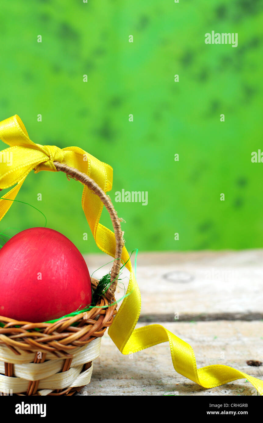 Oeufs de Pâques dans le panier rouge sur fond vert Banque D'Images