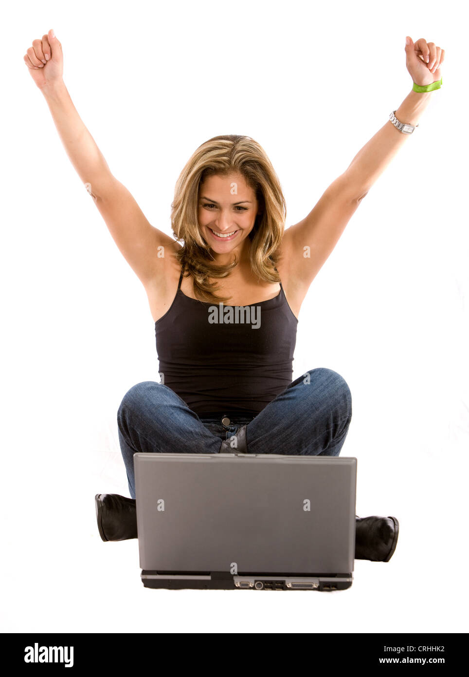 Femme assise devant un ordinateur portable, d'avoir le succès en ligne, avec les bras tendus Banque D'Images