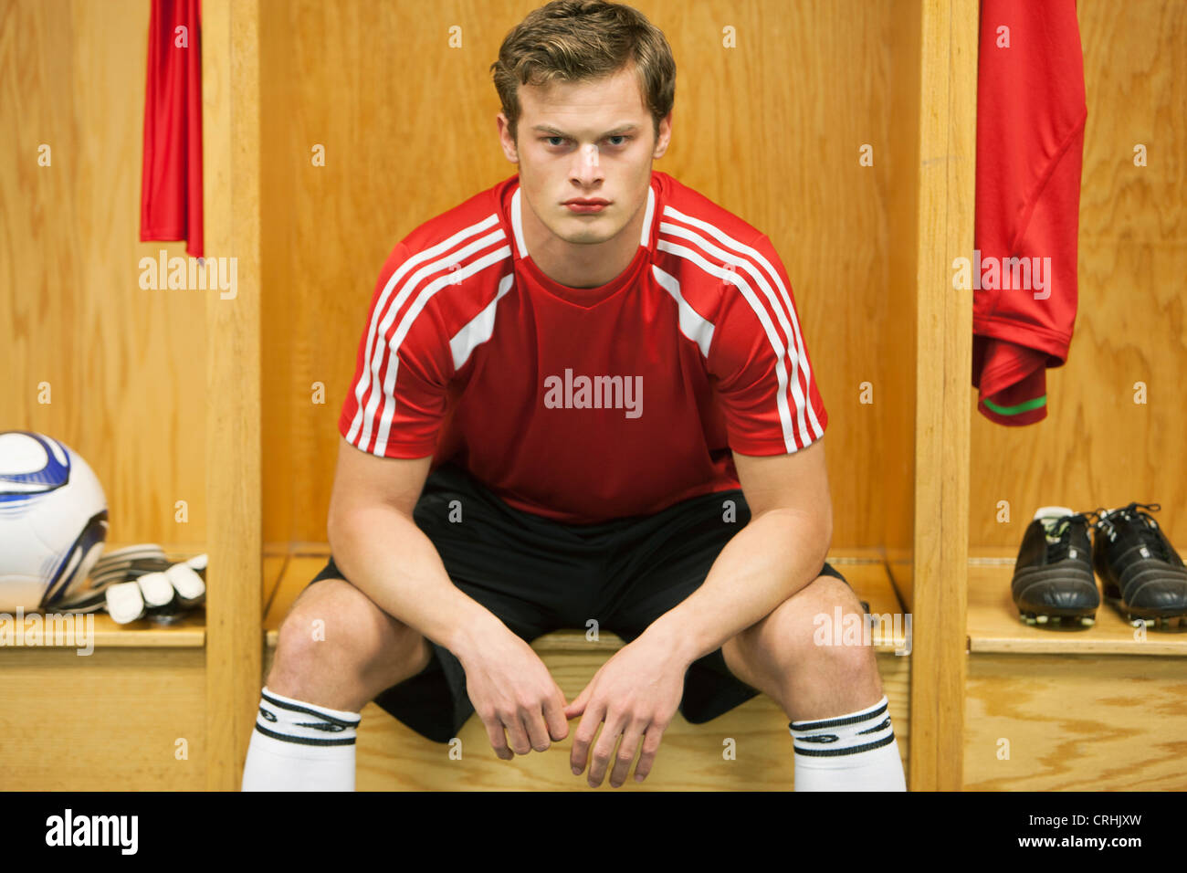 Joueur de foot assis dans le vestiaire Banque D'Images