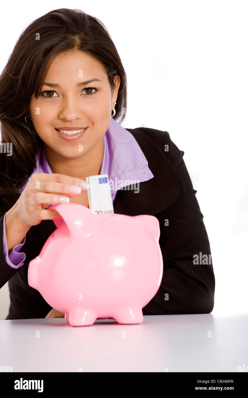 Beautiful businesswoman mettre de l'argent pour ses économies dans une tirelire rose Banque D'Images