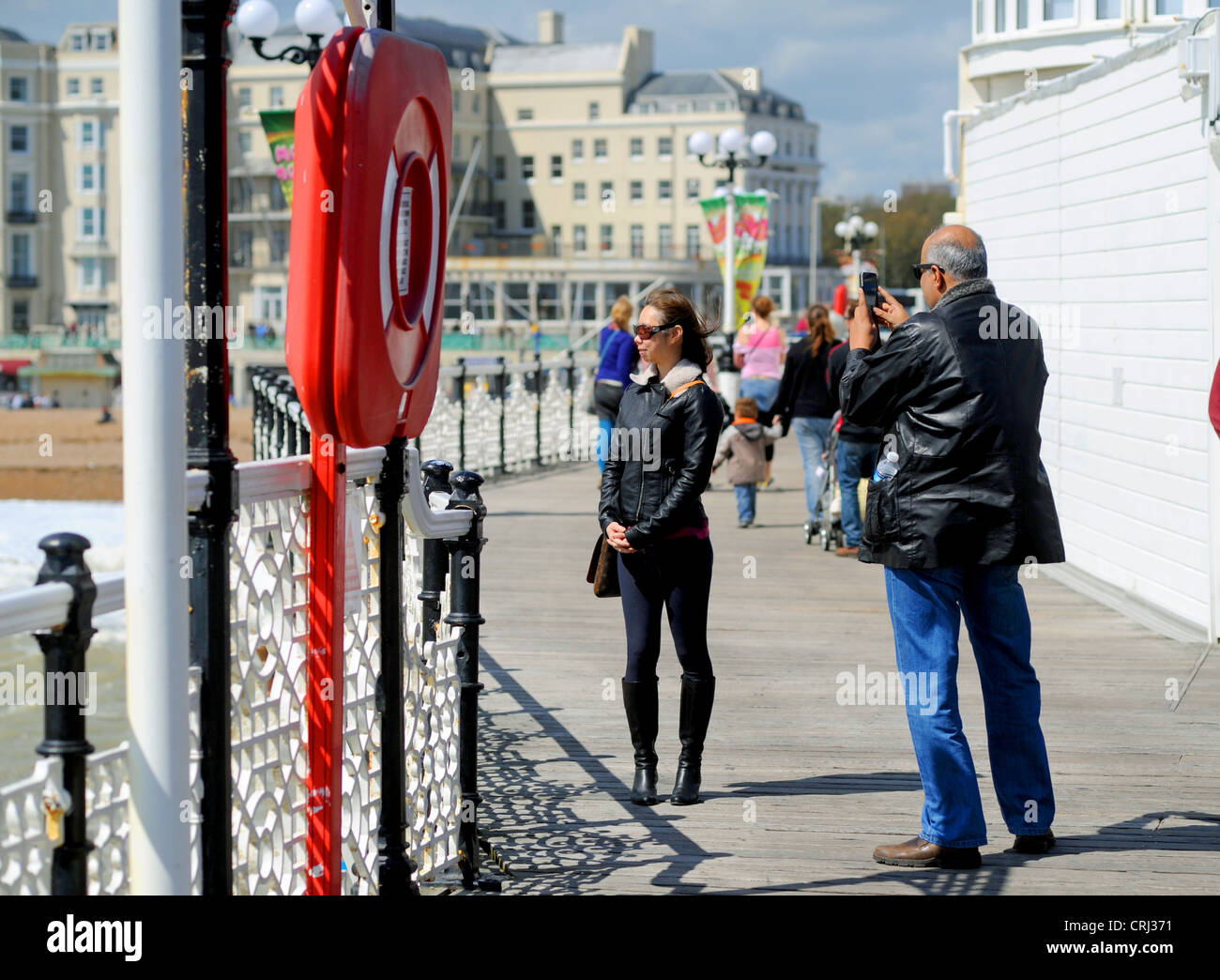 L'homme de prendre une photo de femme en marchant sur la jetée de Brighton Sussex UK Banque D'Images