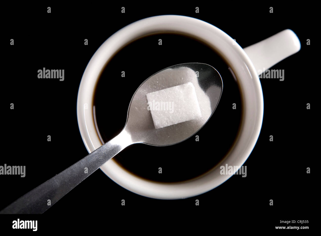 Du sucre est ajouté à une tasse de café Banque D'Images