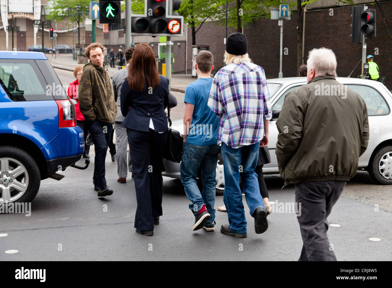 Arrêté de la circulation à travers un passage pour piétons sur une route alors que l'homme vert lumière présente, entraînant les gens à marcher entre les voitures. Nottingham, Angleterre, RU Banque D'Images