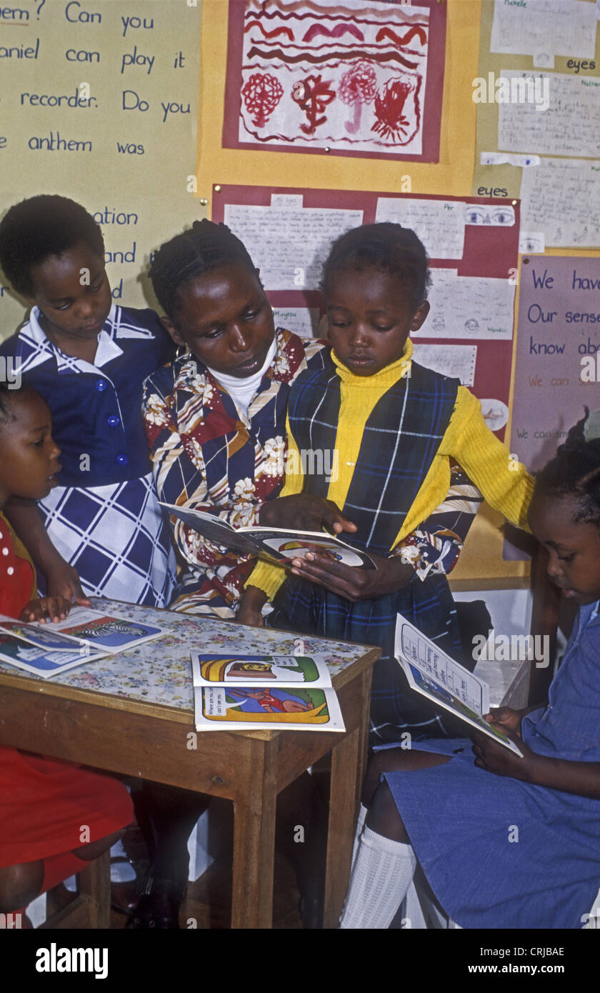 L'Afrique noire dame institutrice avec trois filles les enfants à apprendre à lire avec des livres ouverts Banque D'Images