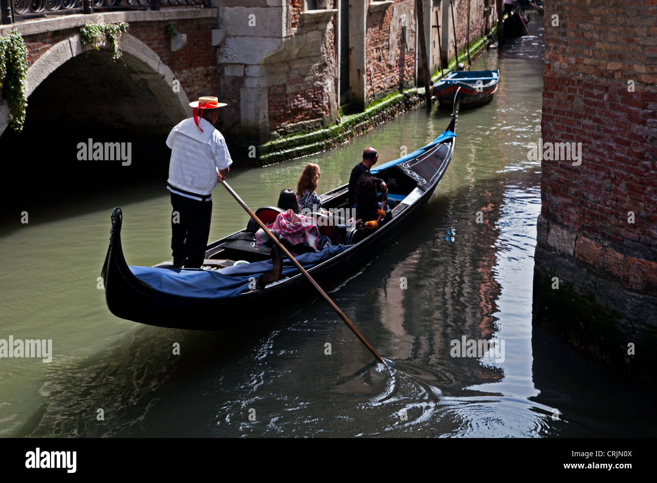 Les passagers prenant Gondolier vénitien sur un voyage sur le canal de lumière tamisée pommelé , Venezia Banque D'Images