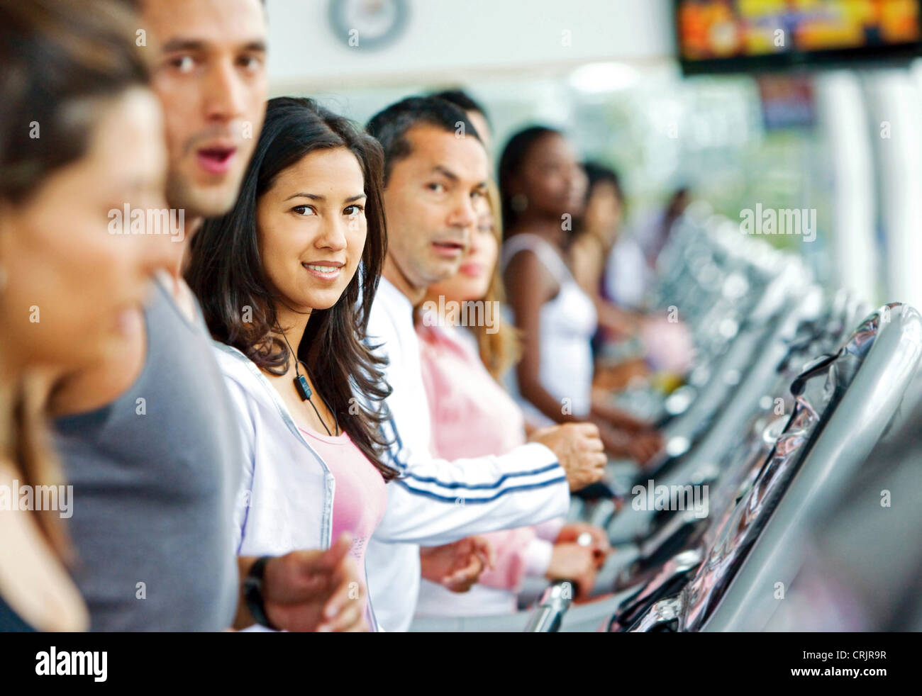 Belle femme dans la salle de sport cardio faire l'exercice avec un groupe de personnes autour d'elle Banque D'Images