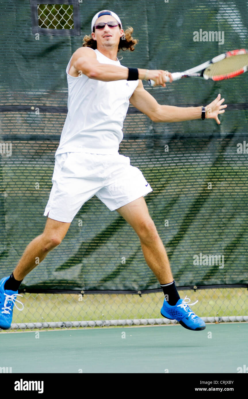 L'homme aux cheveux longs avec des lunettes de soleil suit à travers sur tennis shot. Banque D'Images