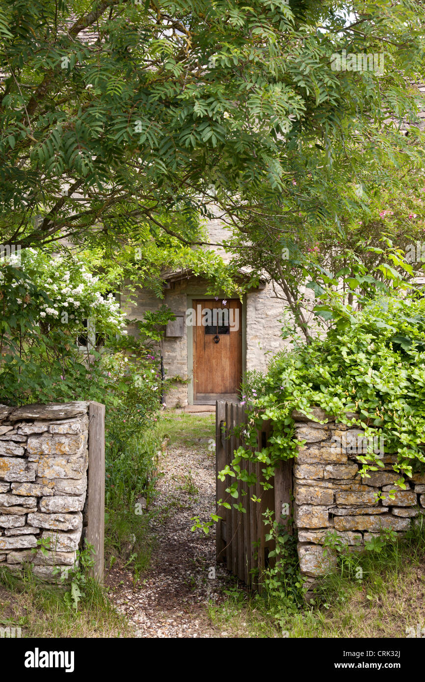 Cotswold cottage en pierre avec porte ouverte dans mur en pierre, Kelmscott, West Oxfordshire, Angleterre, Royaume-Uni Banque D'Images