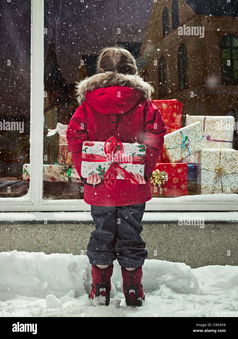 Girl holding Christmas present in snow Banque D'Images