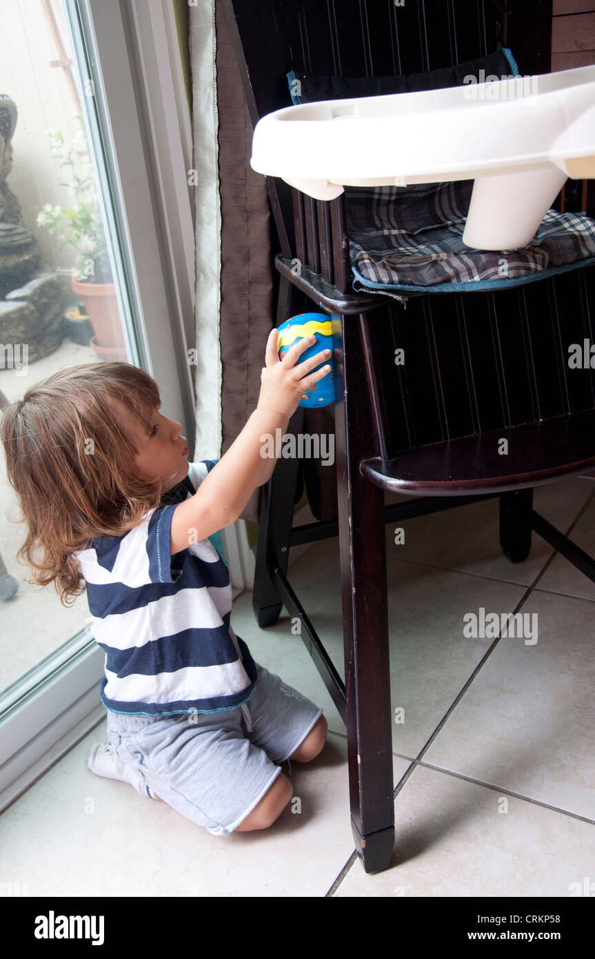 Mignon bébé garçon enfant jouant avec une chaise haute Banque D'Images