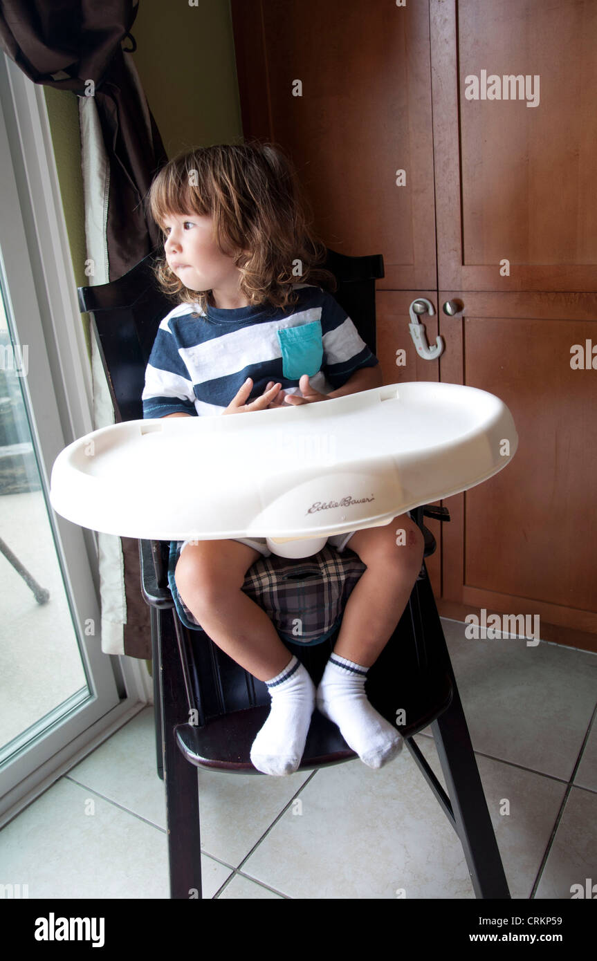 Mignon bébé garçon enfant assis dans une chaise haute Banque D'Images