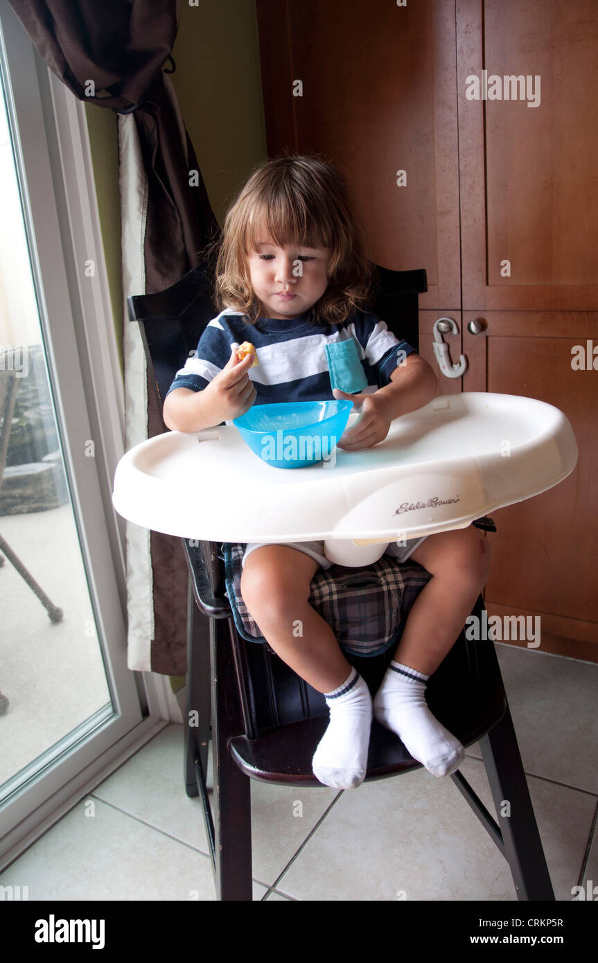 Mignon bébé garçon enfant manger dans une chaise haute Banque D'Images