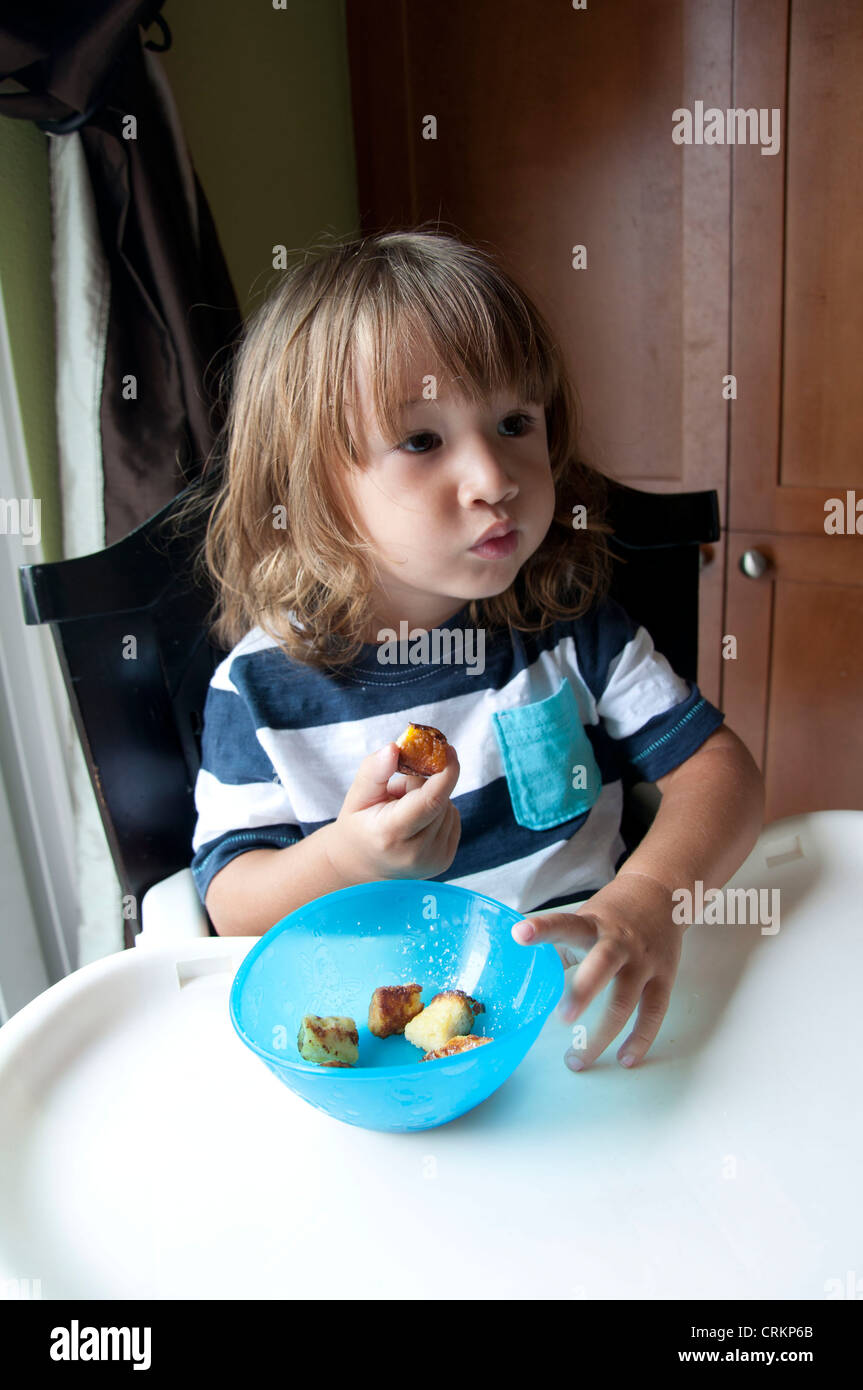 Mignon bébé garçon enfant manger dans une chaise haute Banque D'Images