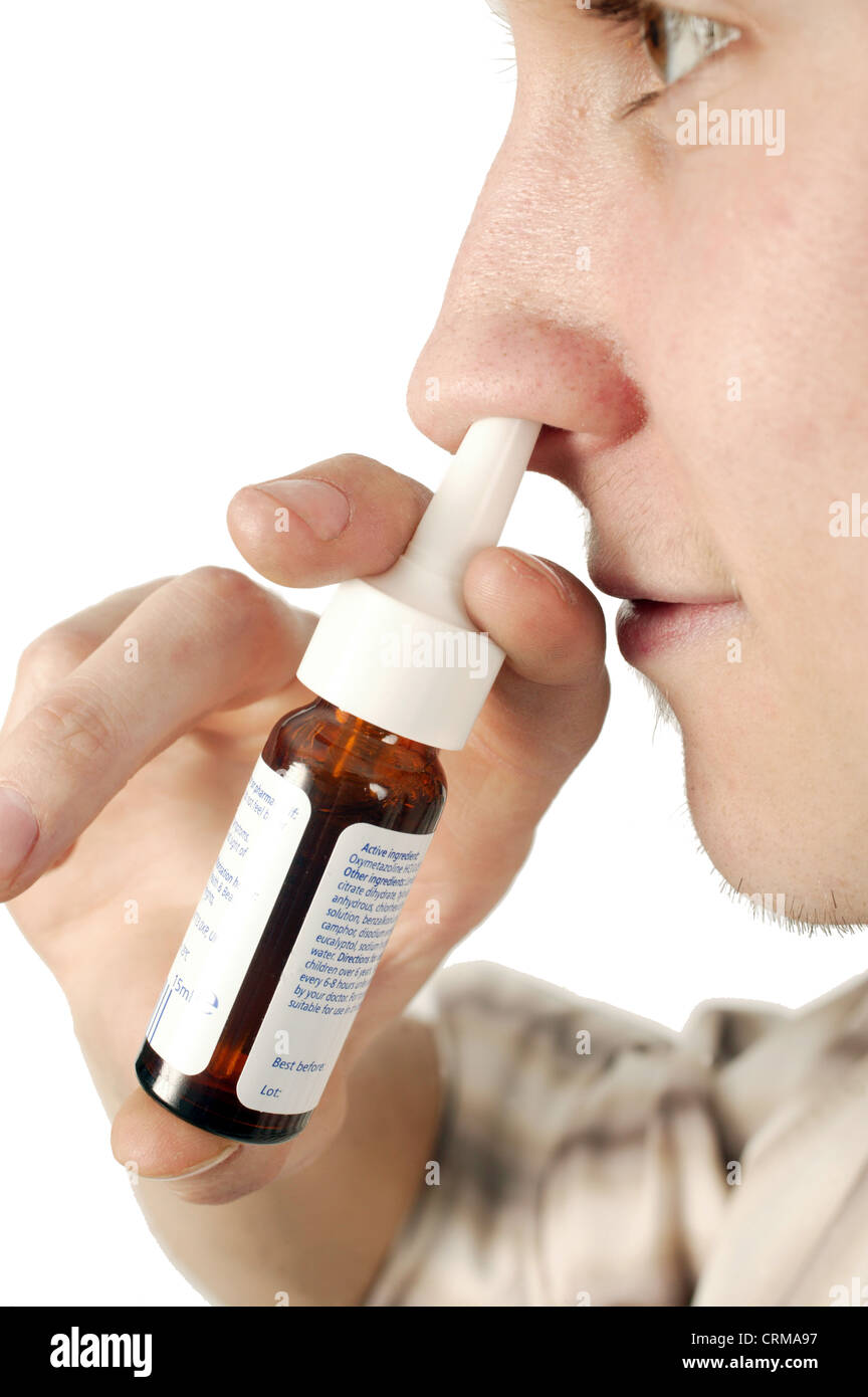 Jeune homme à l'aide d'un spray nasal. Nasal Spray est idéal pour soulager la congestion nasale. Congestion nasale se produit lorsque la membrane qui tapisse le nez gonfle et une accumulation de mucus épais est présent. Ces embouteillages se produit lorsque la victime a le rhume des foins, sinusite, rhume et d'autres allergies. Banque D'Images