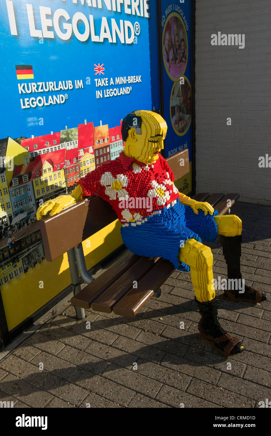Touristiques Lego dormir sur un banc par l'entrée principale du parc Legoland, à Billund, Danemark Banque D'Images