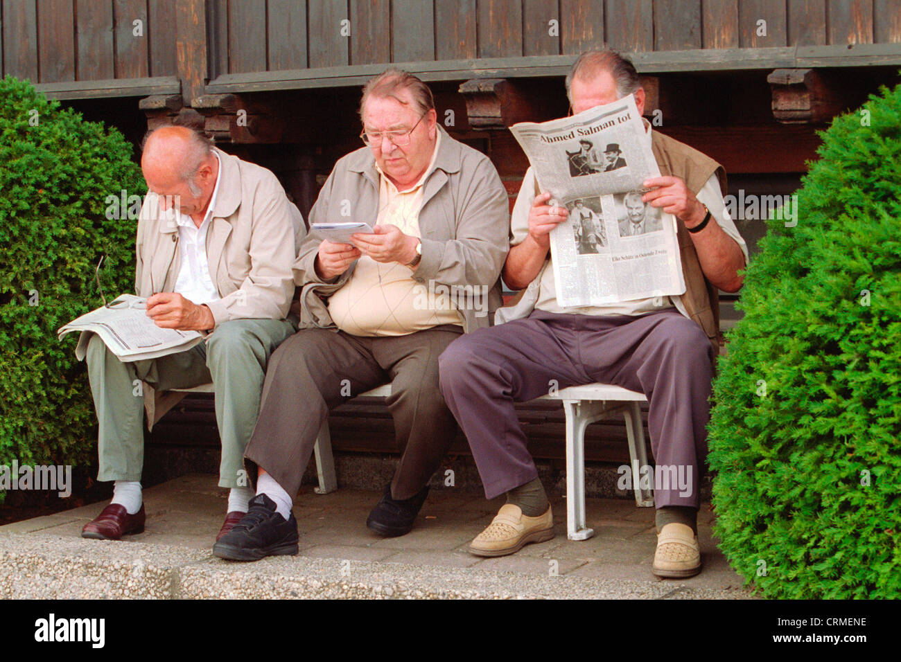 Dresde, trois retraités s'asseoir sur un banc et lire Banque D'Images