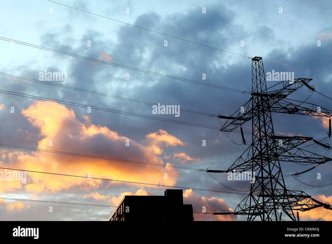 Un pylône d'électricité contre un ciel nuageux au coucher du soleil Banque D'Images