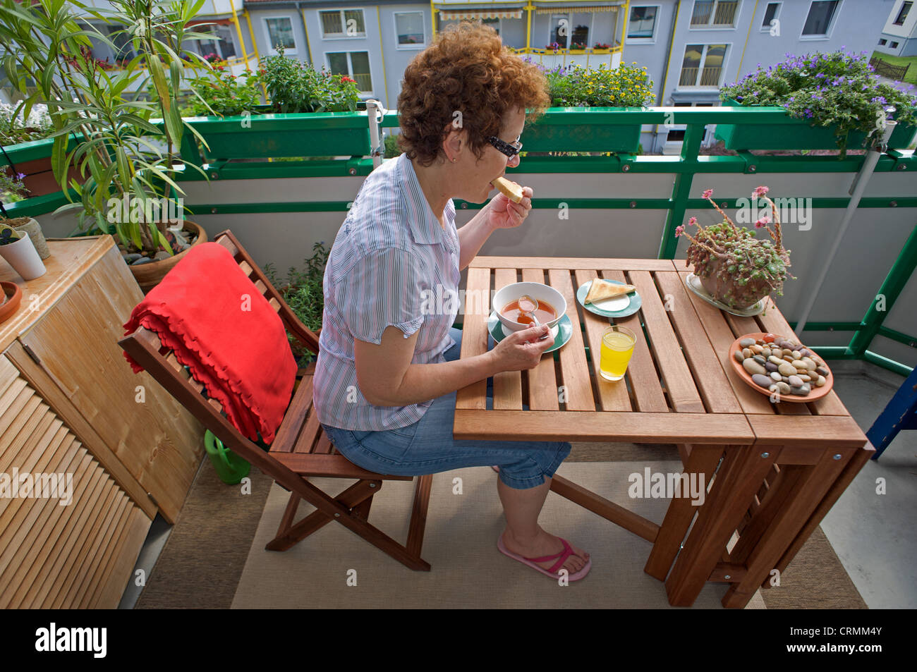 Femme seule de manger le déjeuner sur un balcon d'immeuble Banque D'Images