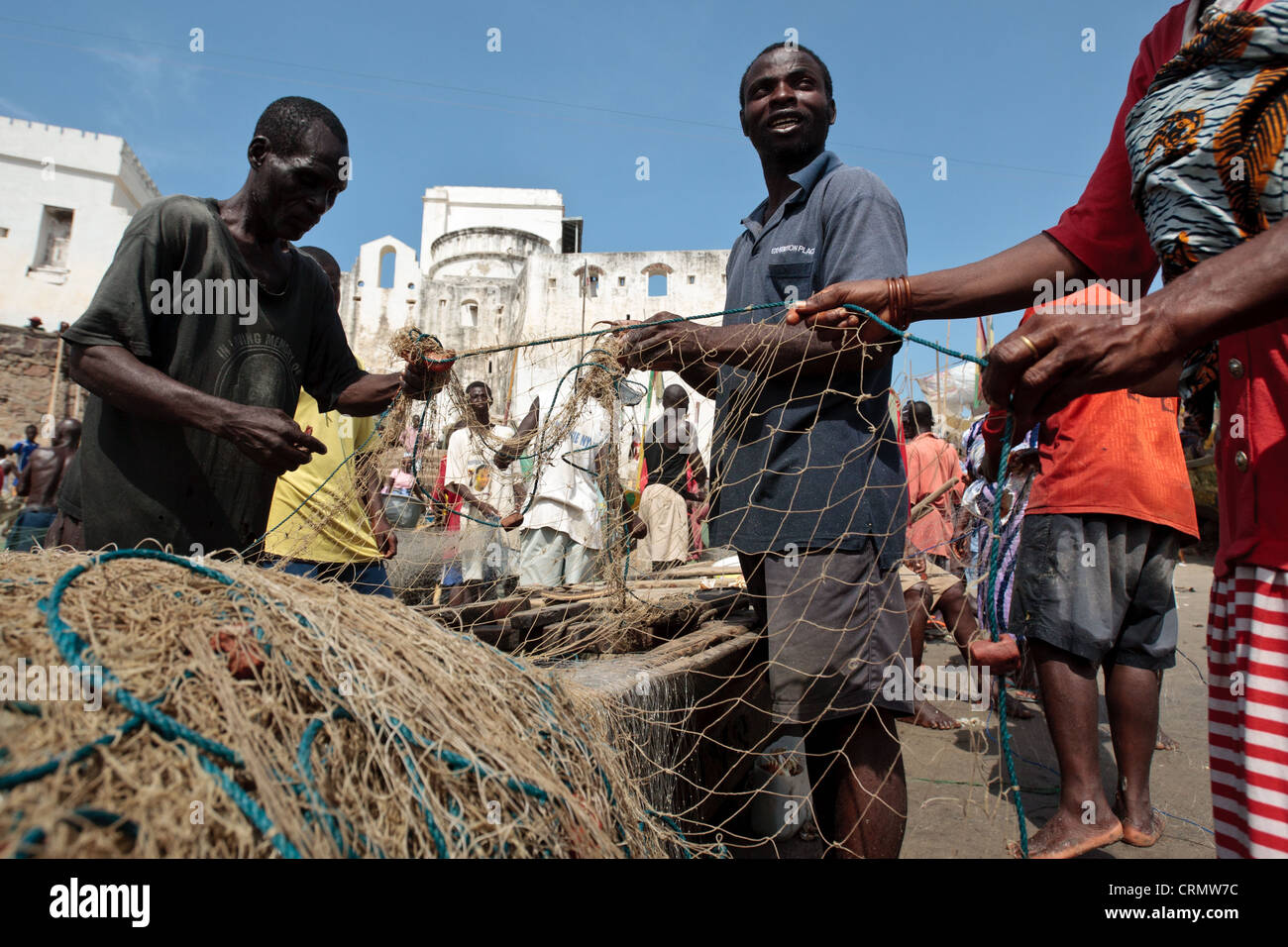 Les pêcheurs réparant les filets de pêche dans la région de Cape Coast, Ghana Banque D'Images