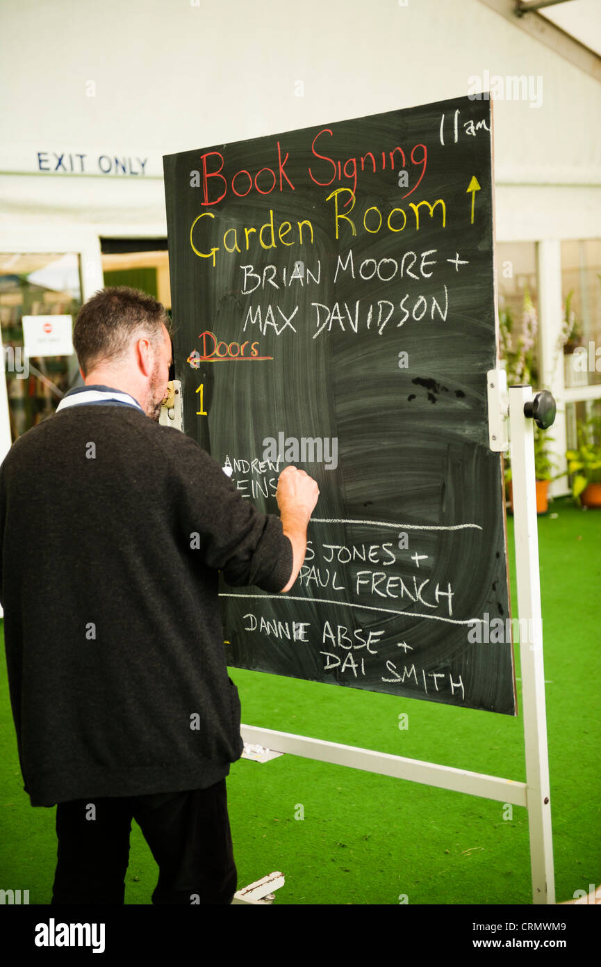Un homme écrit les détails des événements sur un tableau noir à l'Telegraph Hay Festival, Juin 2012 Banque D'Images