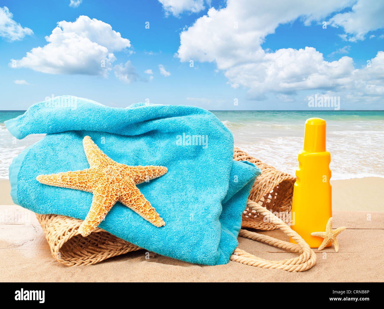 Maison de vacances plage panier avec serviette et crème solaire donnant sur une plage de sable idyllique Banque D'Images