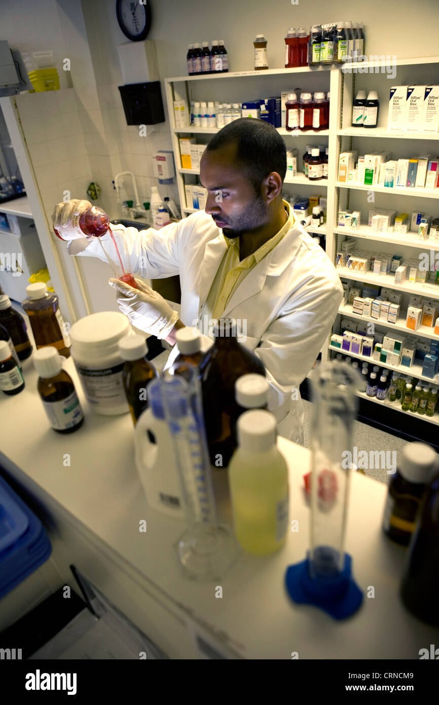 Un pharmacien se déverse un liquide rouge dans un cylindre gradué. Banque D'Images