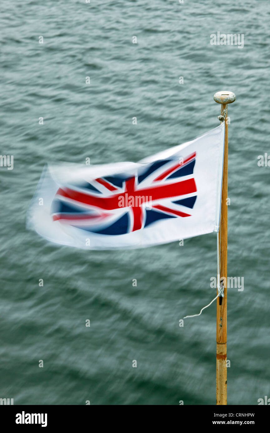 Union Jack flag flottant au vent sur la proue d'un lancement de croisière plaisir Windermere. Banque D'Images