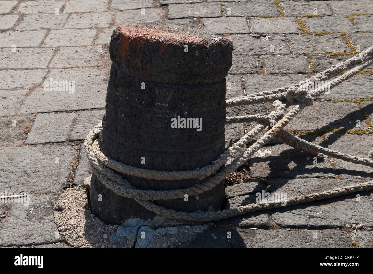 Cordes d'amarrage attachées à un vieux bollard de fer sur un quai de port, Sicile, Italie Banque D'Images
