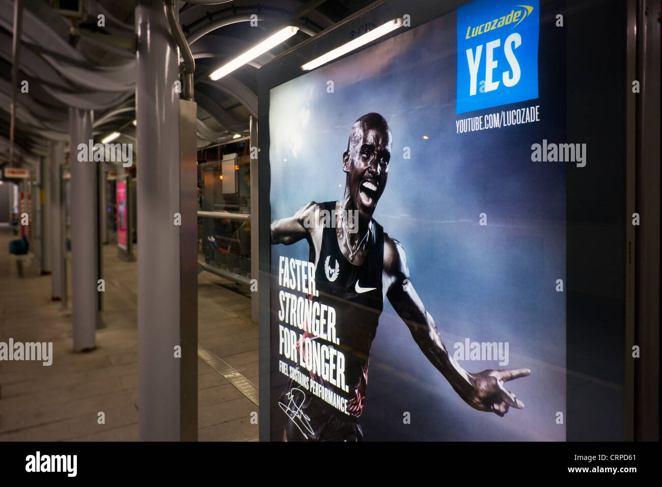 Panneau publicitaire sur une plate-forme du Docklands Light Railway dans la nuit. Banque D'Images