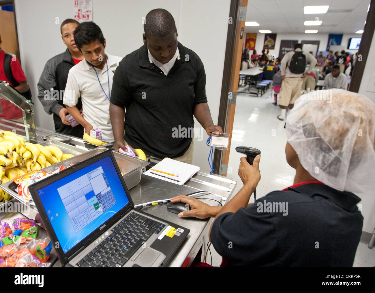 Cafétéria travailleur utilise un scanner à code-barres lu l'information sur les étudiants du déjeuner à l'école publique à cartes charter high school Banque D'Images