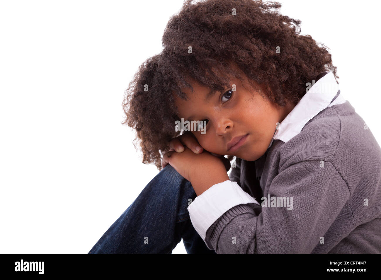 Portrait d'un petit garçon assis sur le plancher, isolé sur fond blanc Banque D'Images
