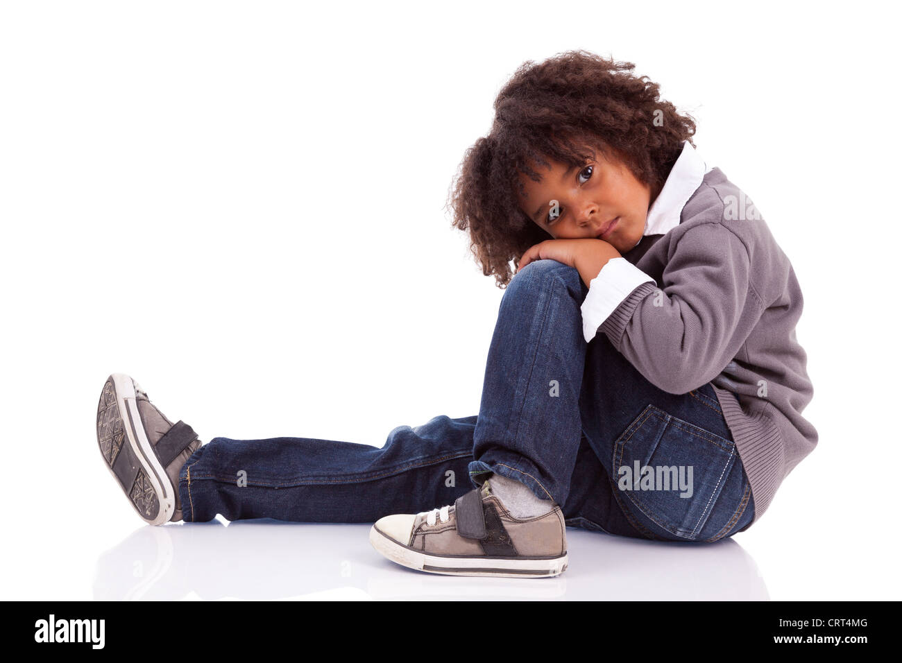 Portrait d'un petit garçon assis sur le plancher, isolé sur fond blanc Banque D'Images