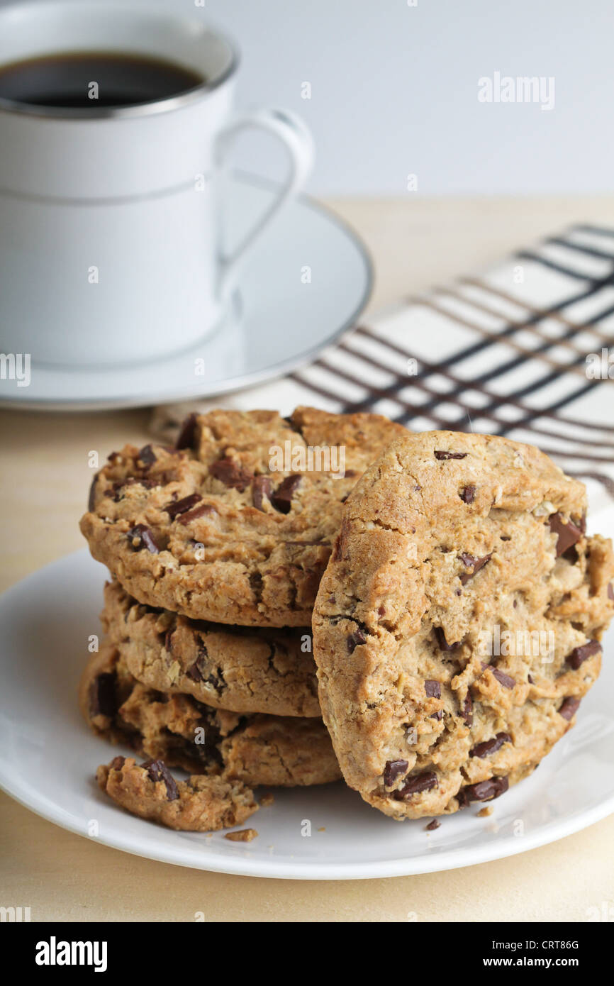 Quatre morceaux de chocolat cookies avec une tasse de café noir. Banque D'Images