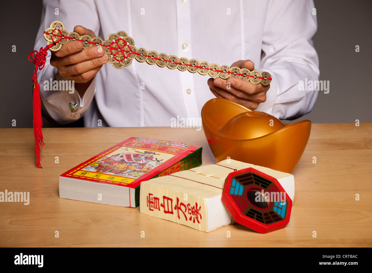Avec les mains de l'homme feng shui chinois accessoires sur table, tenant  une épée faite de pièces Photo Stock - Alamy