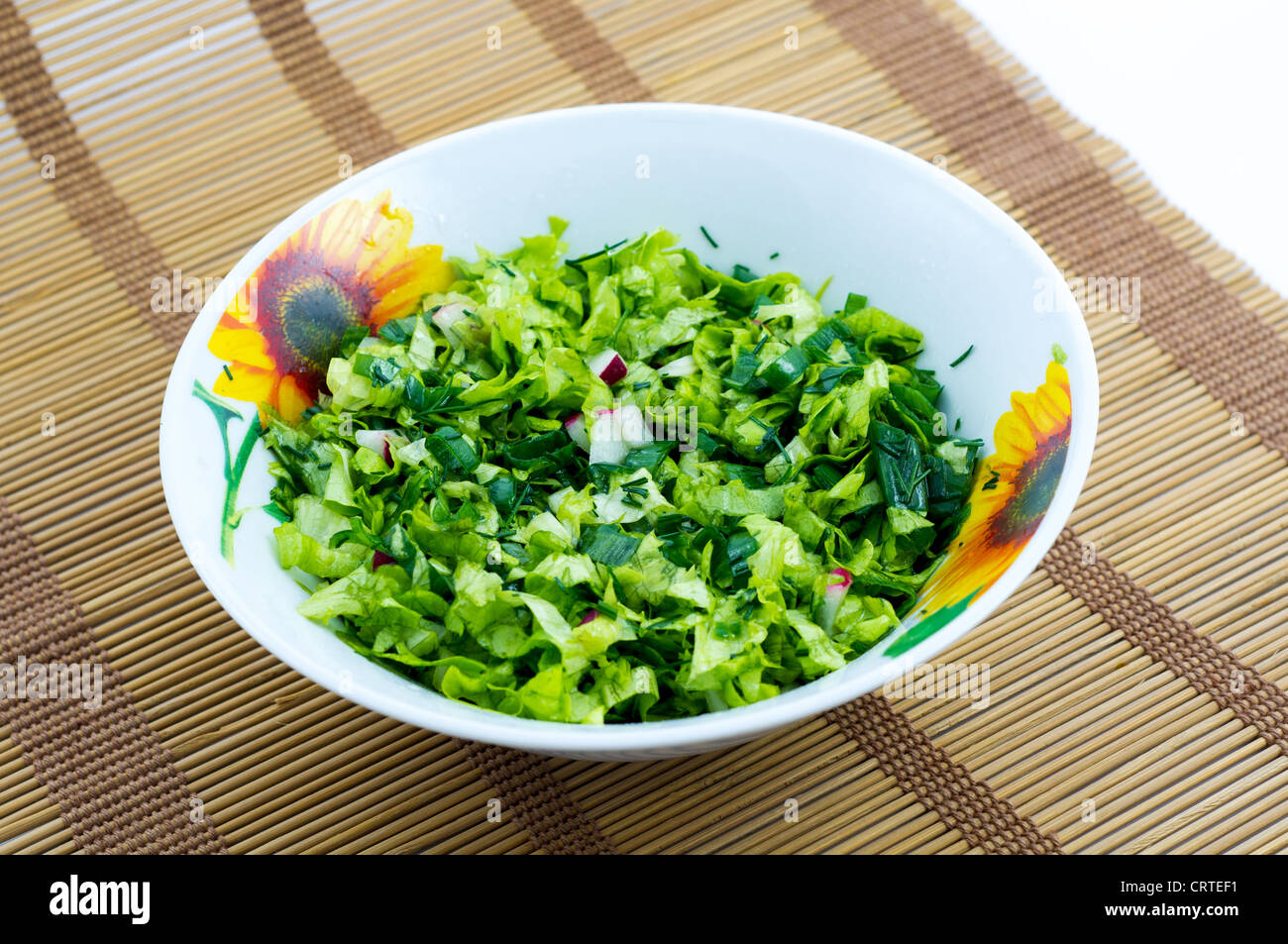 Le bol avec la salade placée sur le plateau de bambou Banque D'Images