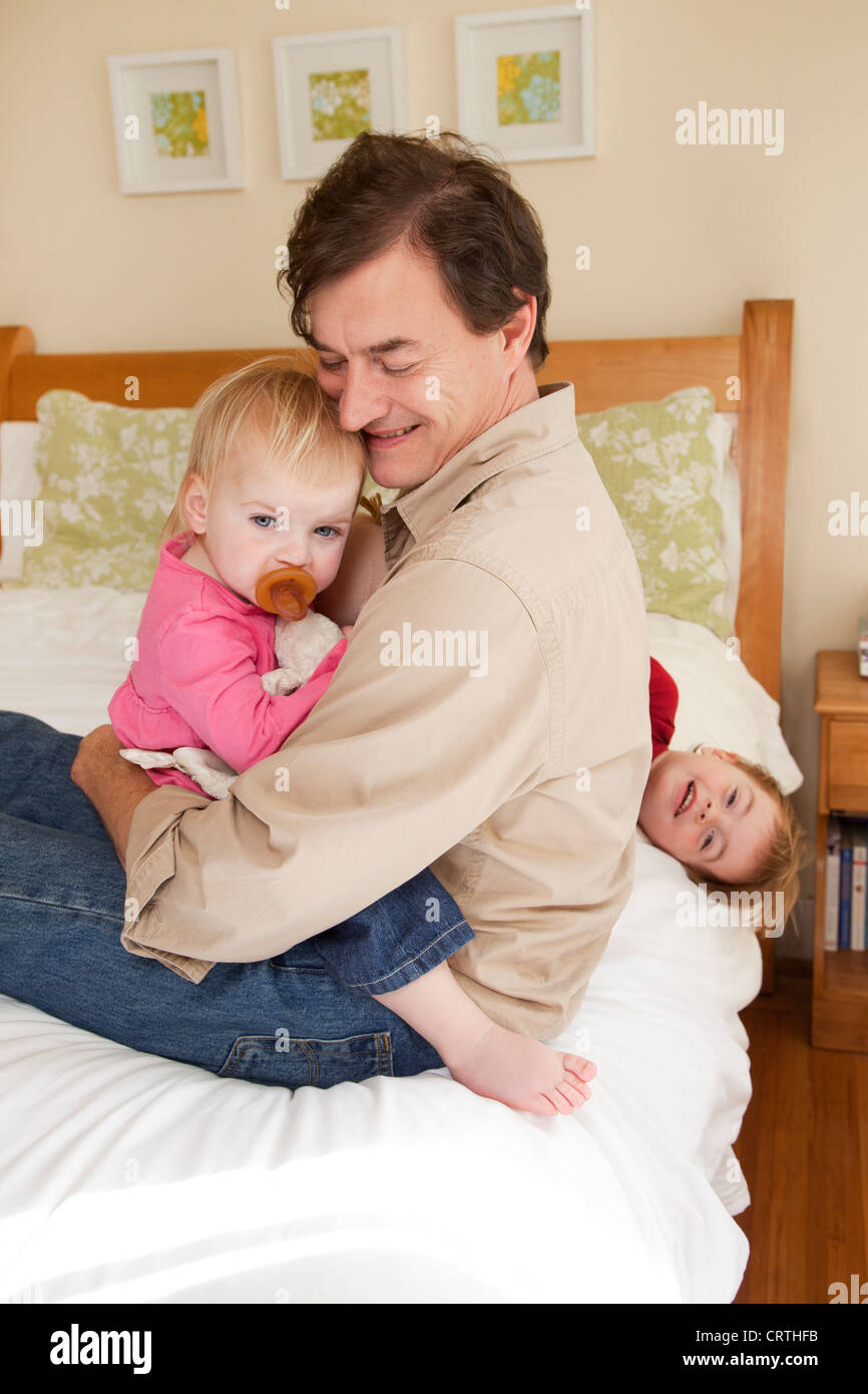 Père est serrant ses enfant fille sur le lit. Banque D'Images