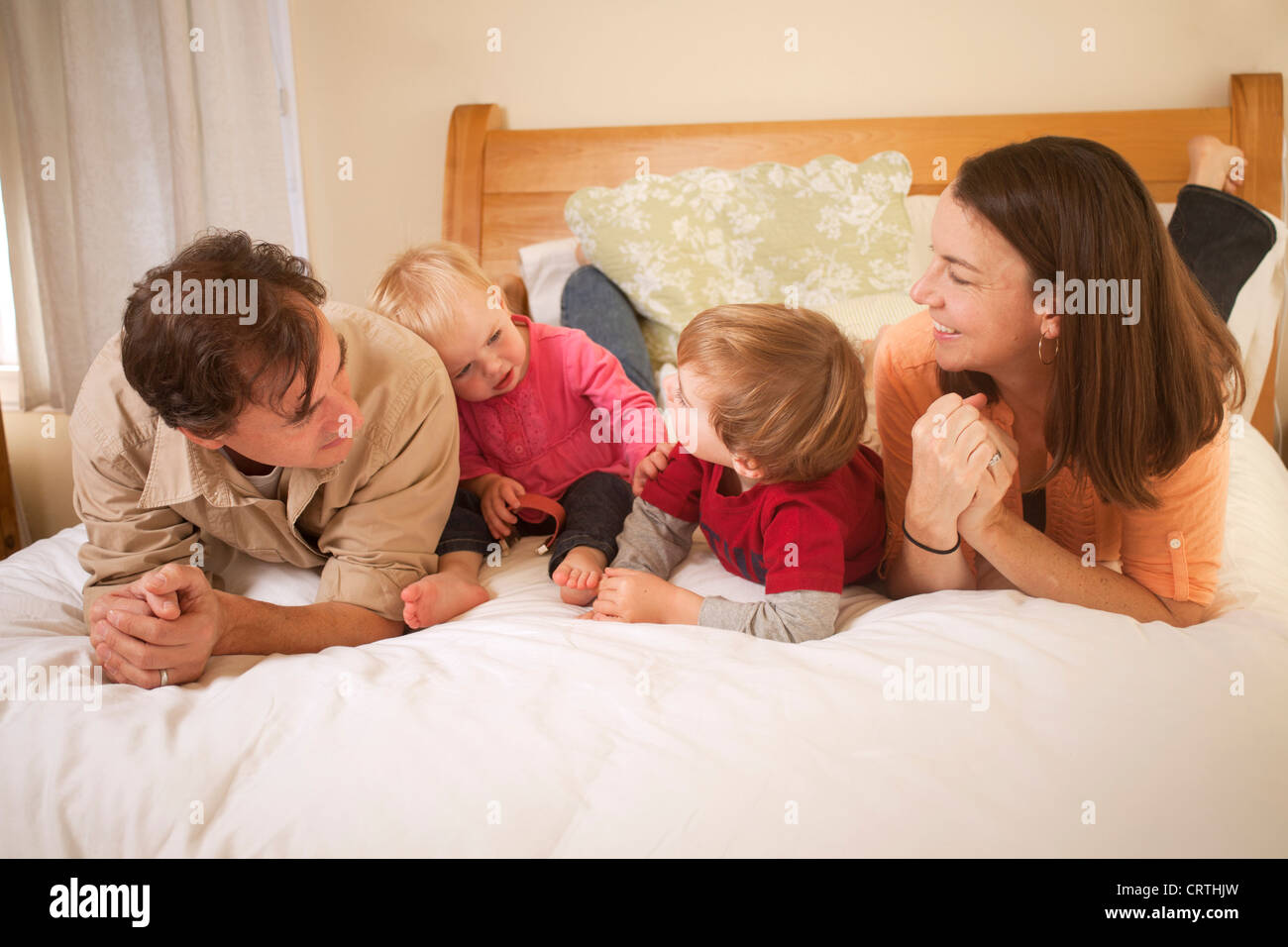 La mère, le père et ses deux enfants sont couchés sur le lit. Banque D'Images