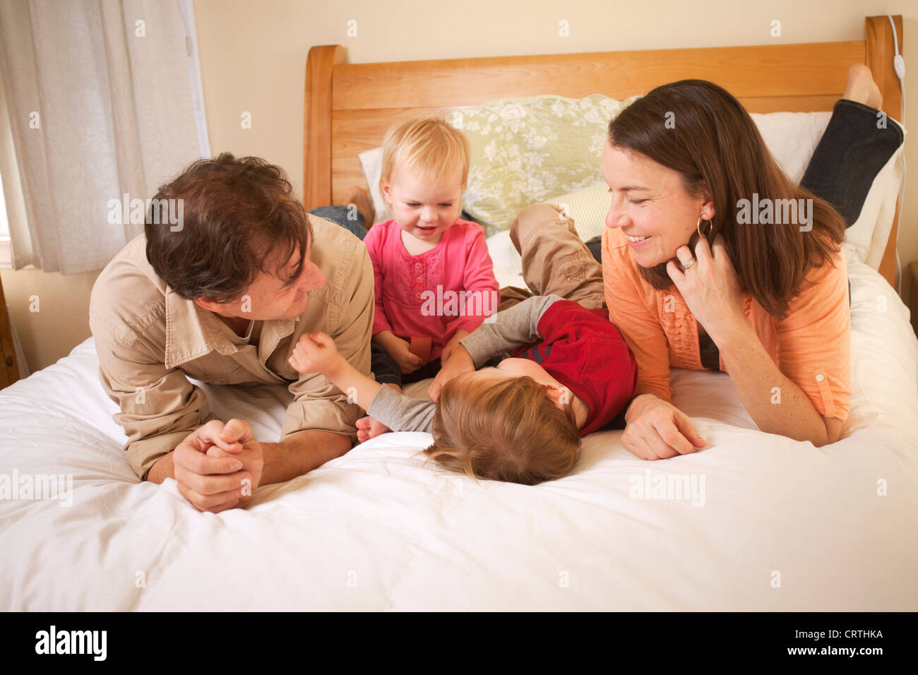 La mère, le père et ses deux enfants sont couchés sur le lit. Banque D'Images