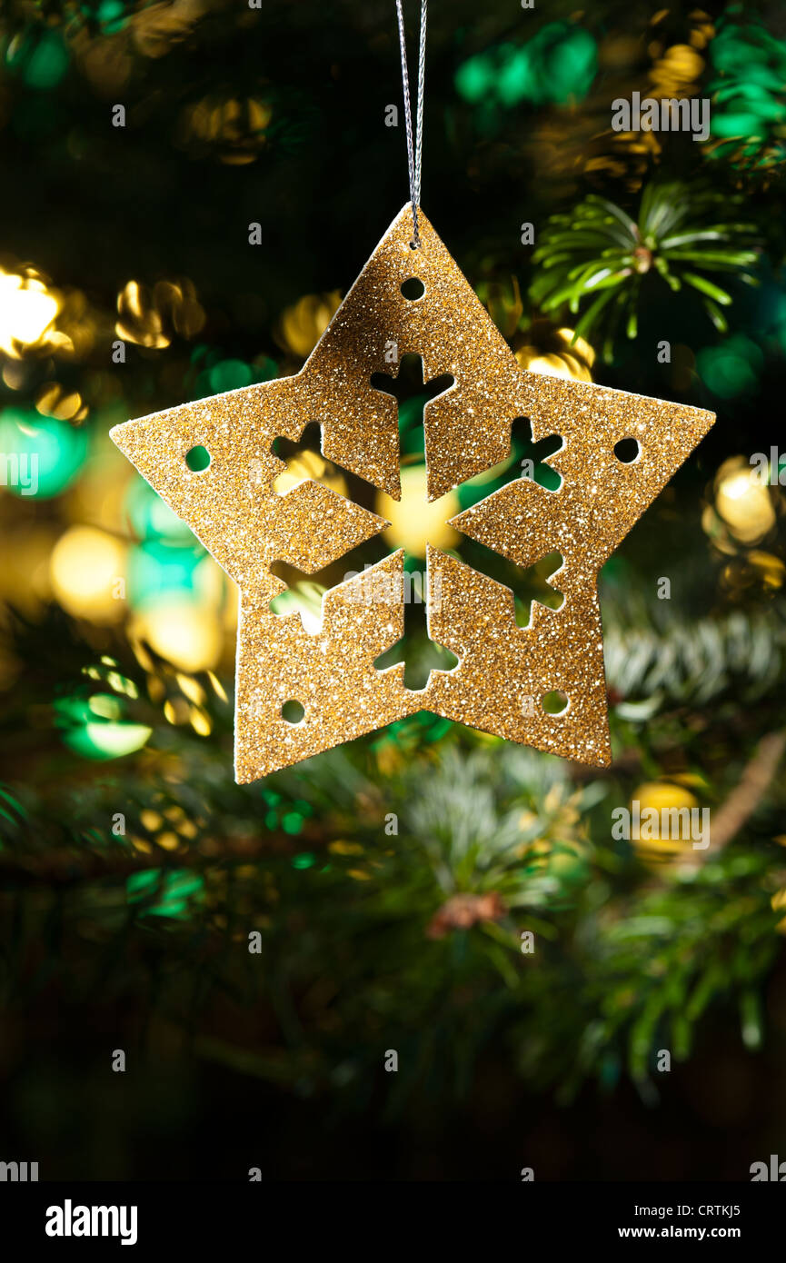 Étoile d'or de décoration ornement dans un arbre de Noël devant un glitter Banque D'Images